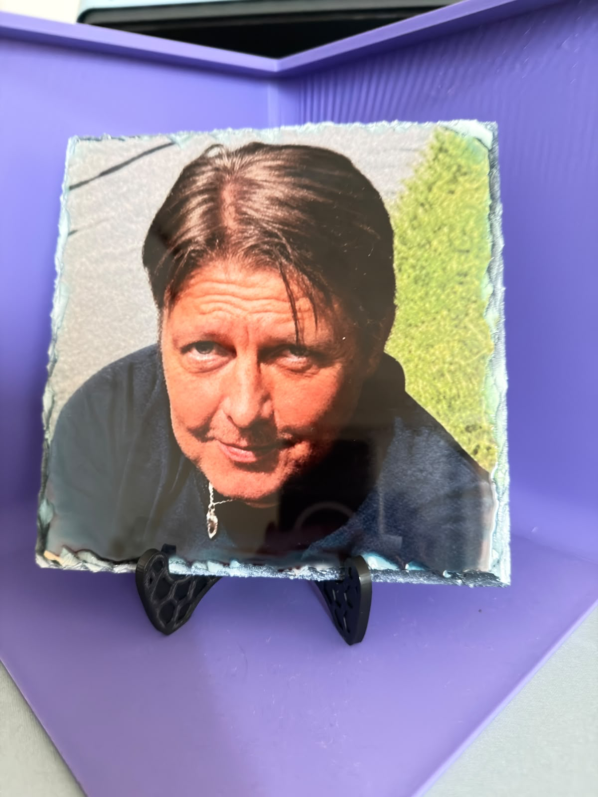 Vierkante fotoleisteen met een kleurenportret op een zwarte standaard.